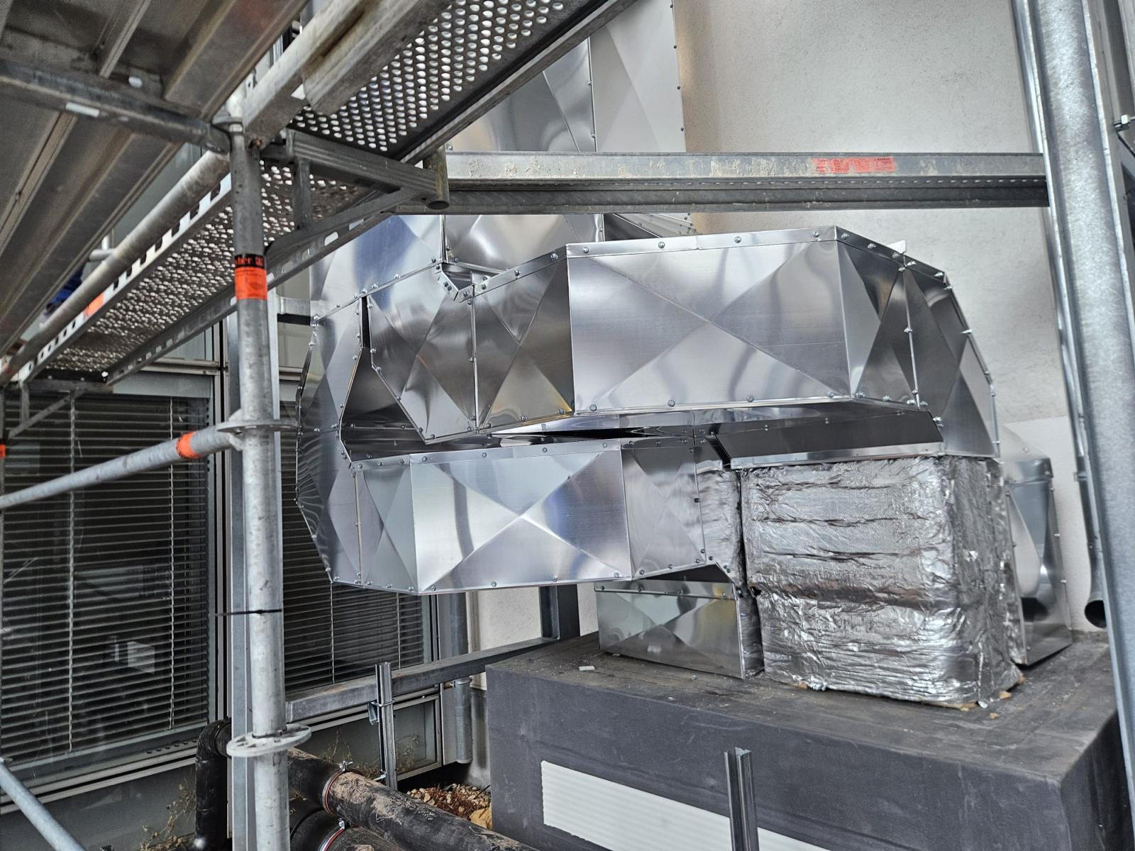 Detaliu de termoizolație la un canal de ventilație, cu vată minerală, folie de aluminiu și manta metalică realizată manual