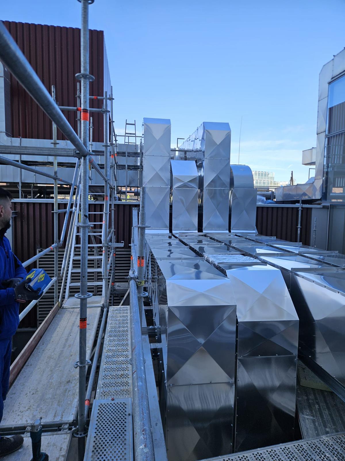 Montator G&D verificând canale de ventilație termoizolate, protejate cu manta metalică, pe un acoperiș industrial