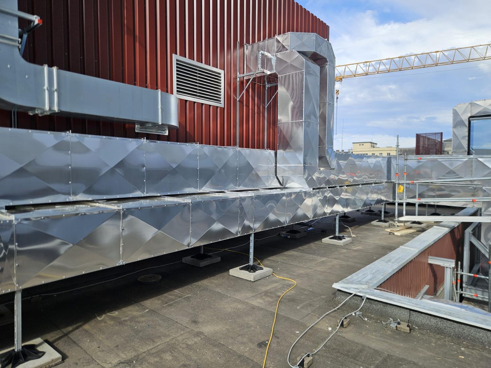 Canale de ventilație termoizolate pe acoperișul unei clădiri industriale, cu manta metalică montată precis